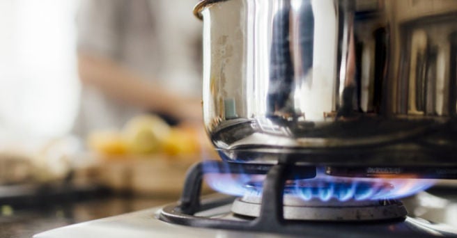 Close up of lit gas hob with saucepan