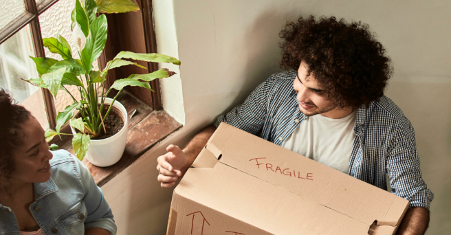 Smiling man carrying a box upstairs